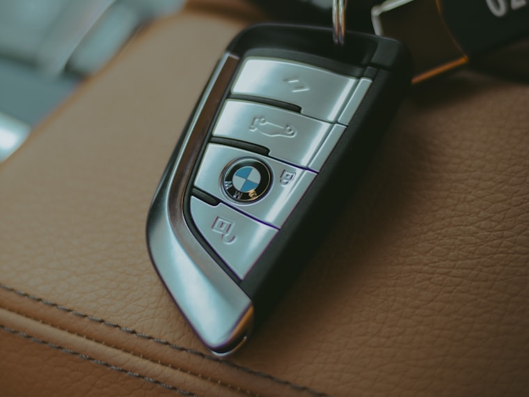 Two modern car keys resting on a leather car seat
